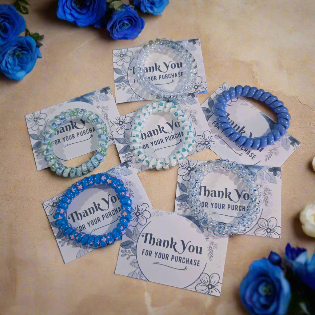 Blue hair ties on white cards with 'Thank You for Your Purchase' text on a wooden surface
